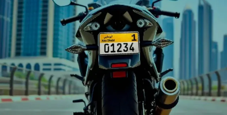 A motorcycle with an Abu Dhabi plate against a cityscape of skyscrapers and a bridge.