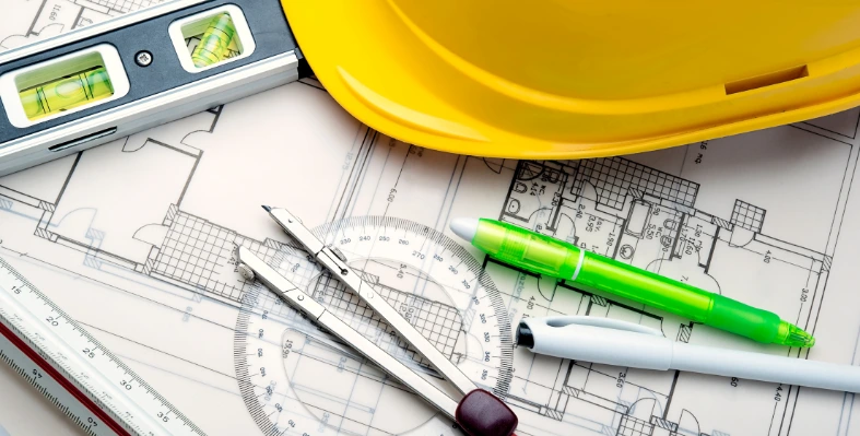 A hard hat and other instruments used in designing and architecture