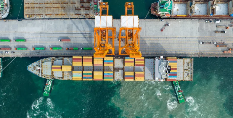 A bird's eye view of a shipping container vessel docked in a port.